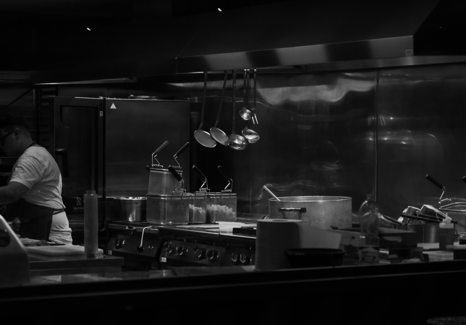 Commercial kitchen cook line beneath a stainless steel extraction canopy